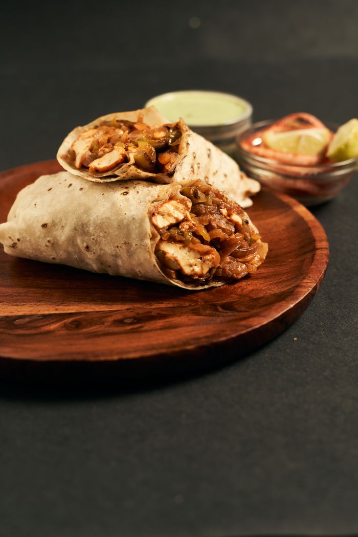 Mouth-watering chicken wraps served with dips on a wooden plate, perfect for lunch.