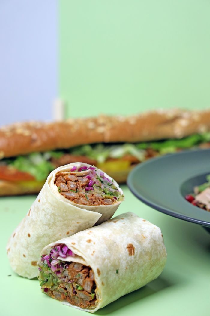 Close-up of a flavorful wrap and sandwich with fresh ingredients on a colorful background.