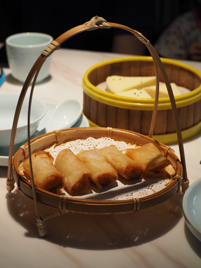 Crispy fried spring rolls served in a bamboo basket, perfect for a delicious homemade meal.